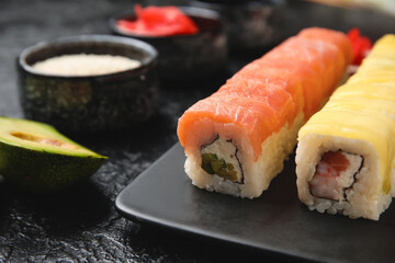 Set of delicious Philadelphia sushi rolls on dark table, closeup