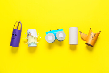 Different figures made of cardboard tubes for toilet paper on yellow background