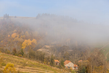 Fototapeta na wymiar Beautiful autumn foggy Carpathian mountains in the early morning. Carpathian village in the morning on autumn mountain hills.