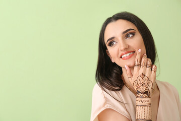 Beautiful Indian woman with henna tattoo on color background