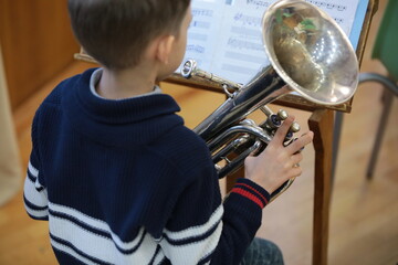 Child playing musical instrument tuba on sheet music portrait from behind close-up