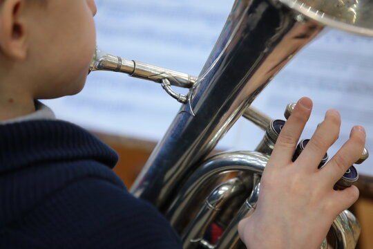 Boy child playing a musical instrument silver trumpet background for music theme close-up