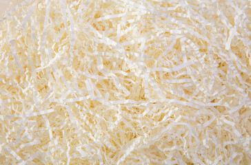 Cream color shredded paper - gift box filler background.