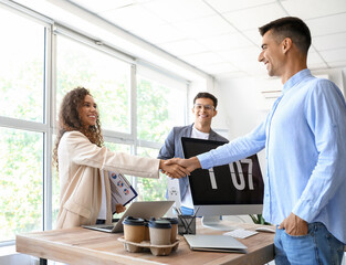 Young business colleagues shaking hands in office