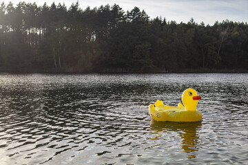 WIelka żółta dmuchana kaczka dryfująca samotnie po jeziorze - obrazy, fototapety, plakaty