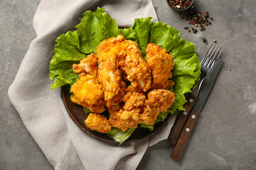 Plate with tasty popcorn chicken and spices on grey background
