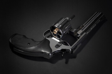 Naklejka premium revolver gun and one bullet on black background