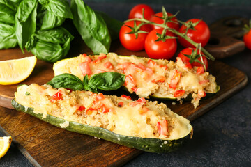 Wooden board with quinoa stuffed zucchini boats on dark background