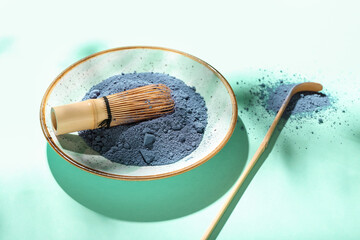 Plate with powdered blue matcha tea, chasen and chashaku on color background