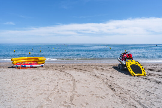 Calle delimitada por bollas sobre el agua del mar en la playa para la salida de veh&iacute;culos de recreo y salvamento un d&iacute;a soleado con cielo azul. Desde playa Burriana, Nerja, M&aacute;laga, Andaluc&iacute;a, Espa&ntilde;a.