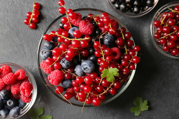 Bowls with different ripe berries on dark background, closeup