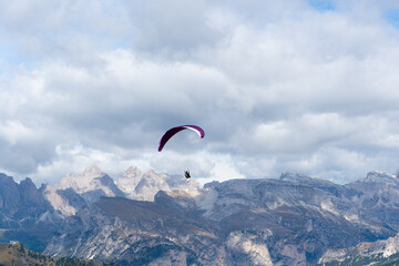 Paraglider silhouette over the snowy mountain peaks of the alps in a cloudy autumn day. Adventure...
