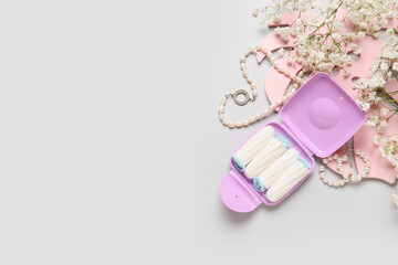 Composition with tampons storage box, necklace and flowers on grey background