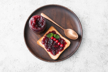 Plate with toast and tasty cranberry jam on light background