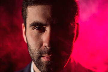Close up photo of man looking at camera on pink background.