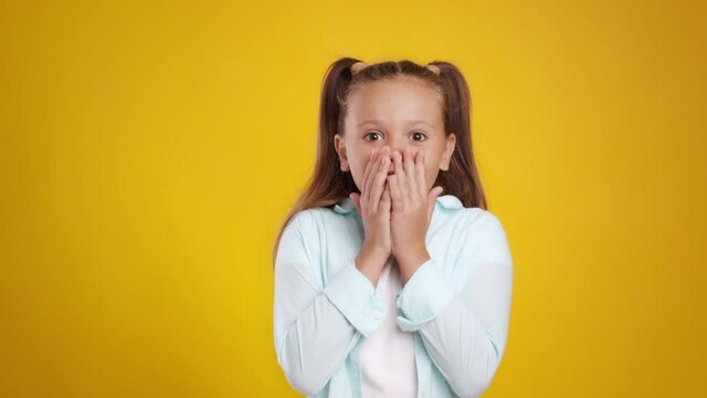 Childhood and fear. Cute little girl feeling afraid and frightened, covering mouth in shock and getting back