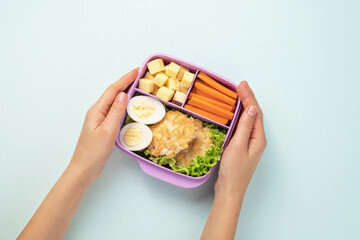 Female hands are holding a plastic lunchbox with lunch