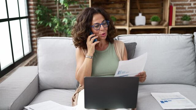 Middle age hispanic woman doing countability with documents and laptop