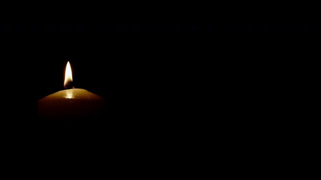 Close up light candle isolated on black background left side of picture shot in 4k super slow motion