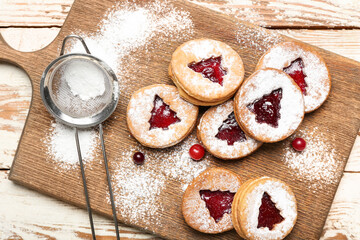 Board with tasty Linzer cookies, cranberry and powdered sugar on table