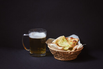 Beer and focaccia bread with pesto sauce on dark background.