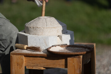 grinding wheat with stone mill - obrazy, fototapety, plakaty