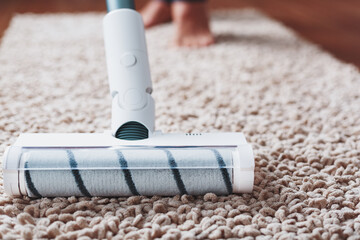 The turbo brush of a cordless vacuum cleaner cleans the carpet in the house in close-up