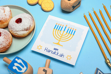 Different symbols of Hanukkah and greeting card on color background