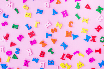 multicolored letters of the English alphabet on a pink background, letters background. Education concept.