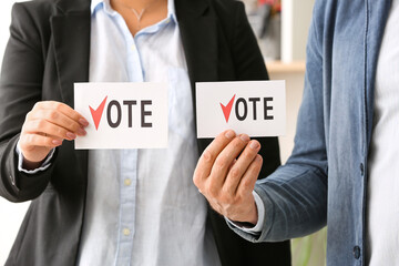 Obraz premium People holding papers with text VOTE at polling station