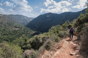 Fototapeta na wymiar A female hiker hiking on the scenic trail to Ein Tamir Spring in Kziv stream, Montfort Nahal Kziv National park, Northern District of Israel, Israel. 