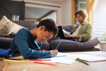 Fototapeta premium Boy drawing on paper on coffee table at home