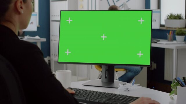 Close up of computer with horizontal green screen on desk. Woman with business job working on monitor with mockup template and isolated background for technology with chroma key.