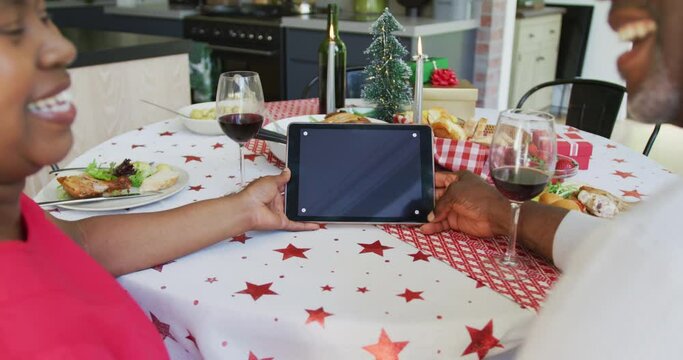 Happy african american senior couple on video call on tablet with copy space at christmas time