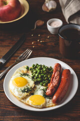 Breakfast with fried eggs, sausages and green peas