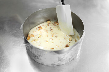 Close-up of a female pastry chef's hands pouring mousse into a mold.