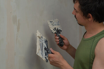 Man doing repairs. worker applies with putty to the wall. working process