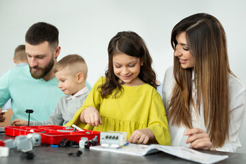 Family with children in a robotics club makes a robot controlled from a constructor.