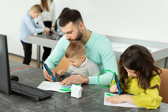 Young father with his son and daughter draw a drawing using a 3D pen in robotics classes