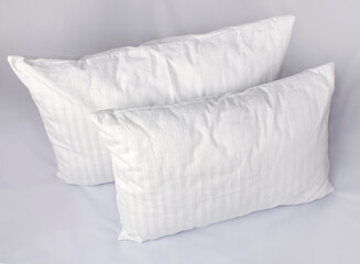 Two white pillows in striped cotton pillowcases. Satin jacquard bedding and accessories. Air soft pillows filled with swan down and bamboo