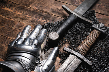 Knight swords and chain mail on the wooden table close up background.