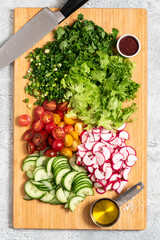 Cooking vegetable salad. Chopped vegetables and herbs on a cutting board top view. Diet or vegan food concept. Salad ingredients on a cutting board.