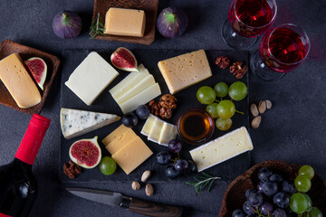 Cheese varieties, grapes, figs and nuts on a slate plate. Wine snacks for a holiday party. View from above