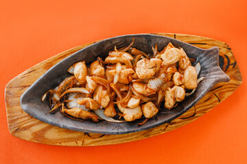 Fish-shaped frying pan with fried chicken and vegetables