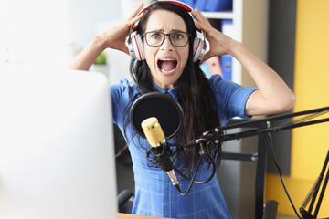 Young woman shouts in headphones in front of microphone