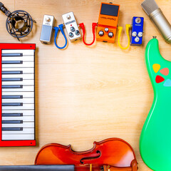 musical instruments on wooden background. guitar, violin, piano, microphone, pedal effect on desk....