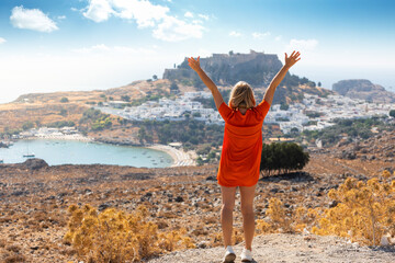 A blonde woman looks at the panorama of Lindos on the island of Rhodes, Greece