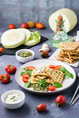 Ready-to-eat delicious zucchini waffles, tomatoes, basil and pumpkin seeds on a plate on the table. Vegetable diet food. Vertical view