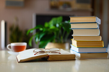 An old open book with glasses lies in the room on the light table at home.  Selective focus on glasses