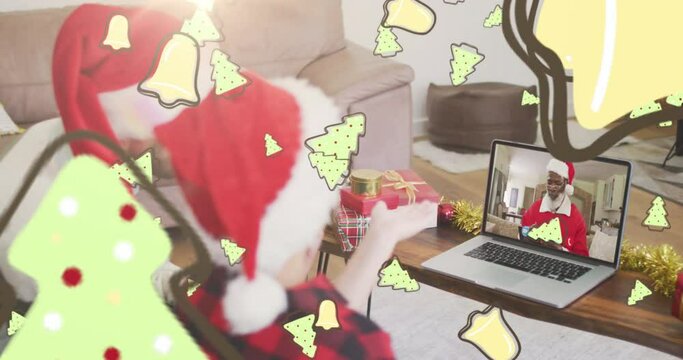 Animation of christmas cookies over caucasian father and son in santa hats on laptop video call